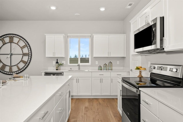 kitchen featuring light countertops, stainless steel appliances, white cabinetry, and a sink
