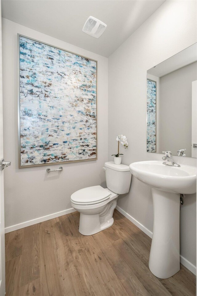 bathroom featuring toilet, baseboards, visible vents, and wood finished floors