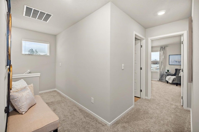 corridor featuring visible vents, carpet, and baseboards