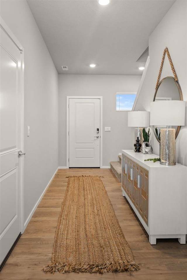 hallway featuring light wood-style floors, stairs, recessed lighting, baseboards, and visible vents