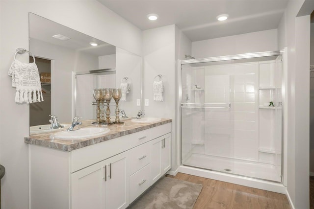 full bathroom featuring wood finished floors, a sink, and a stall shower