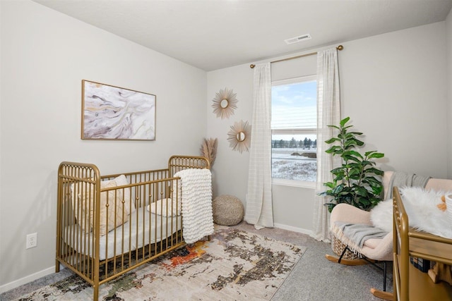 bedroom with baseboards, carpet flooring, a nursery area, and visible vents