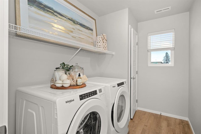 washroom with laundry area, visible vents, baseboards, light wood-style flooring, and washer and clothes dryer