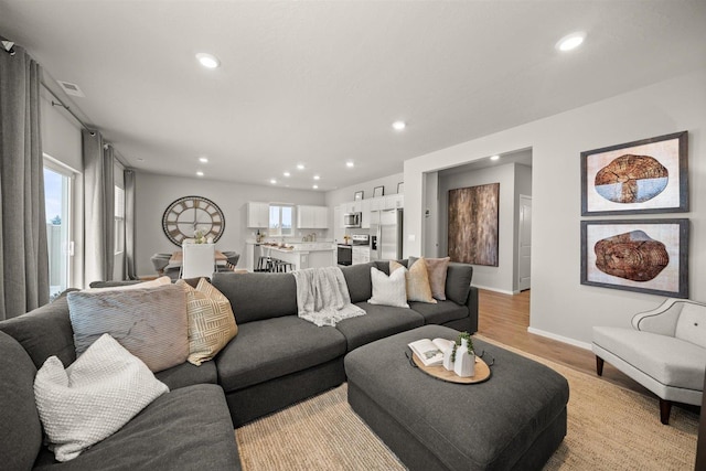 living area featuring baseboards, light wood-type flooring, and recessed lighting