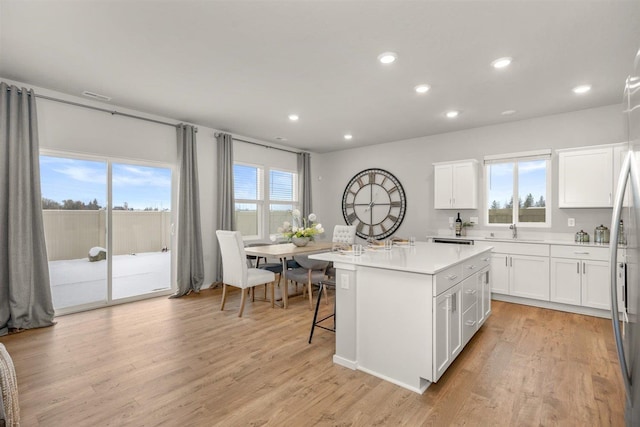 kitchen with a kitchen island, recessed lighting, light countertops, white cabinetry, and a sink