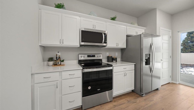 kitchen with white cabinets, stainless steel appliances, light countertops, and light wood-type flooring