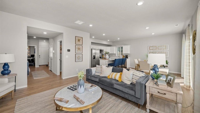 living room with light wood-style floors, recessed lighting, and baseboards