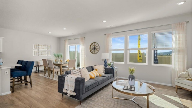 living room featuring recessed lighting, baseboards, and light wood finished floors