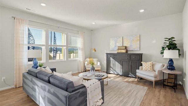 living room featuring light wood-style floors, baseboards, recessed lighting, and visible vents