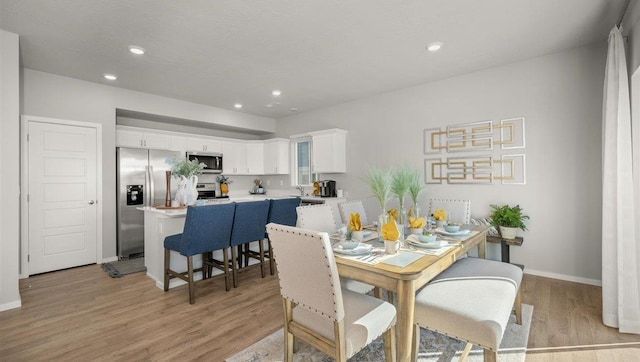 dining space with light wood-type flooring, recessed lighting, and baseboards