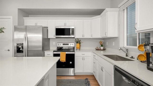 kitchen featuring white cabinets, appliances with stainless steel finishes, a sink, and light countertops