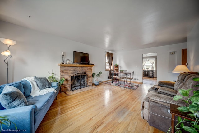 living area with visible vents, light wood-style flooring, and a brick fireplace