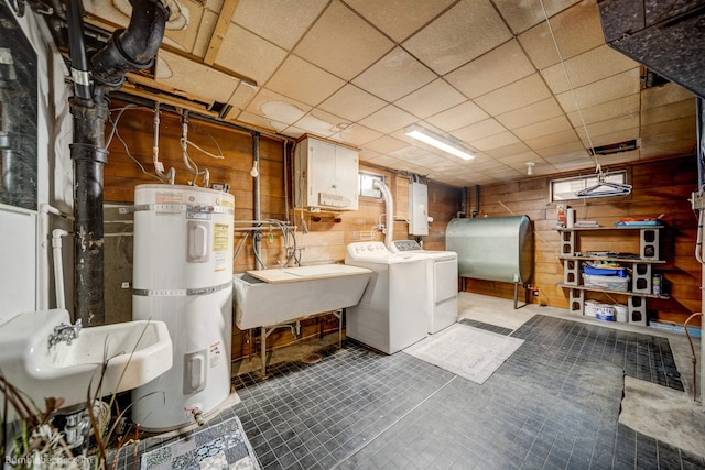 clothes washing area featuring laundry area, strapped water heater, a sink, separate washer and dryer, and heating fuel
