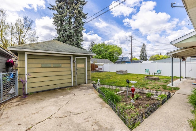 detached garage featuring concrete driveway and fence