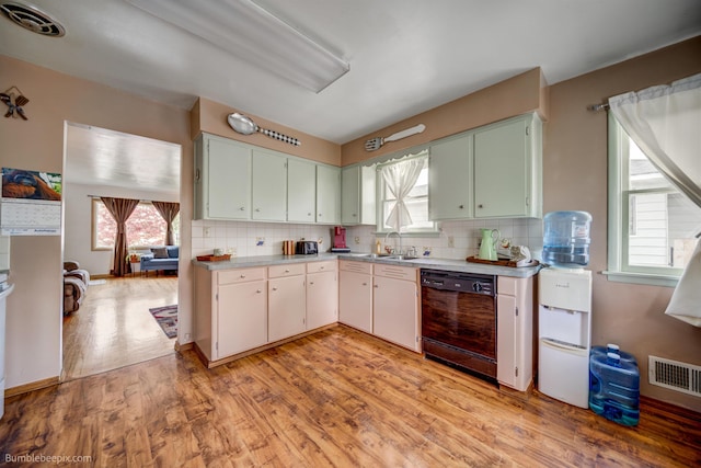 kitchen featuring visible vents, tasteful backsplash, light countertops, black dishwasher, and light wood-style flooring