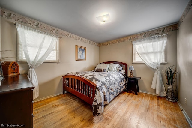 bedroom with baseboards, multiple windows, and light wood-style flooring