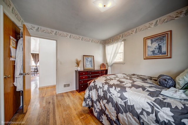 bedroom featuring baseboards, visible vents, and light wood-style floors