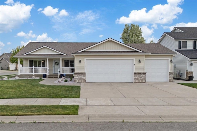 view of front of house with covered porch, a garage, brick siding, a front lawn, and concrete driveway