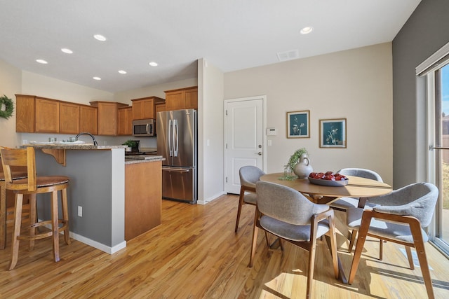 kitchen featuring recessed lighting, appliances with stainless steel finishes, brown cabinetry, and light wood finished floors