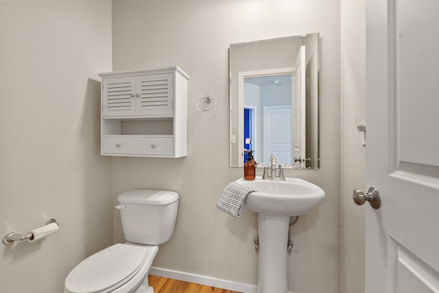 bathroom featuring baseboards, a sink, wood finished floors, and toilet