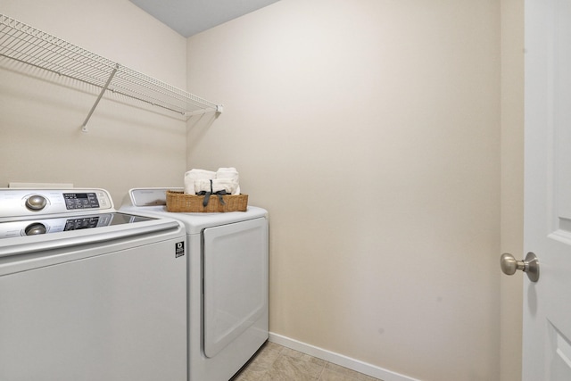 clothes washing area with washing machine and clothes dryer, light tile patterned floors, laundry area, and baseboards