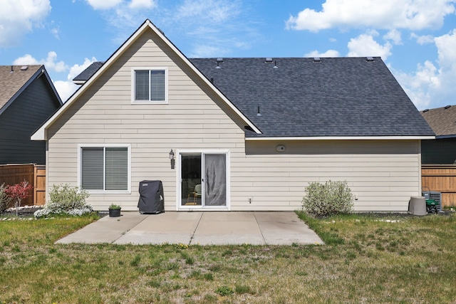 rear view of house featuring fence, a patio, a lawn, and roof with shingles