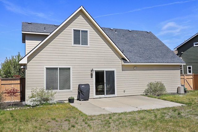 back of property featuring fence, a patio, a lawn, and roof with shingles