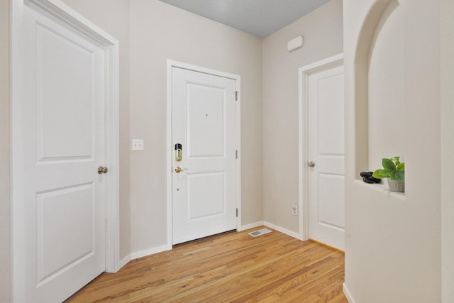 foyer entrance with baseboards, visible vents, and light wood-style flooring
