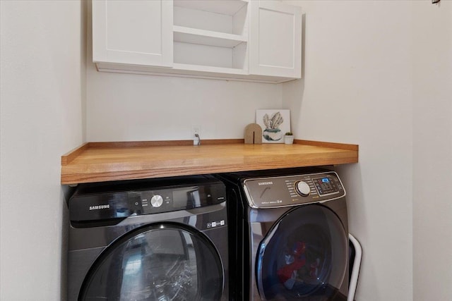 clothes washing area with cabinet space and washing machine and dryer