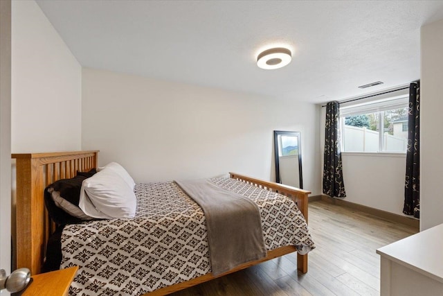 bedroom with baseboards, wood finished floors, and visible vents