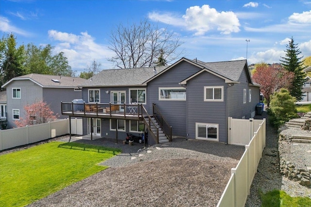 back of property with a fenced backyard, a wooden deck, a yard, and stairway