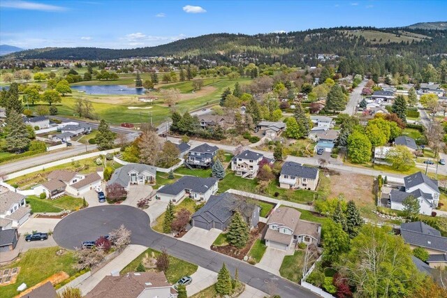 aerial view featuring a residential view, golf course view, and a water and mountain view
