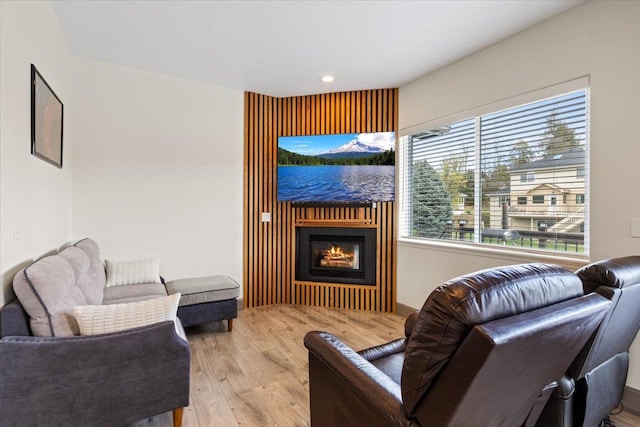 sitting room featuring recessed lighting, a glass covered fireplace, and wood finished floors