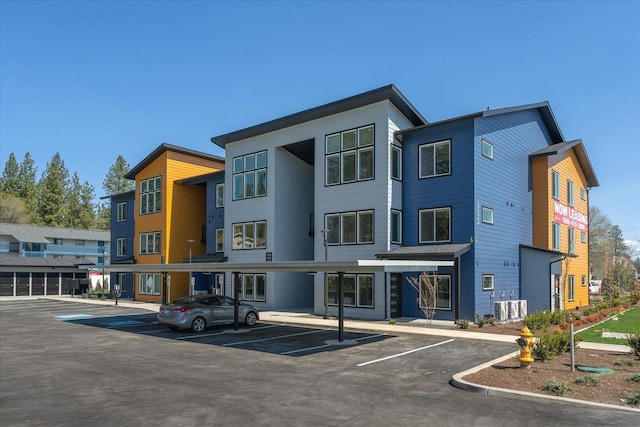 view of building exterior with covered and uncovered parking