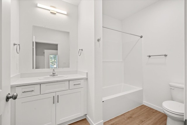 bathroom with vanity, wood finished floors, toilet, baseboards, and  shower combination