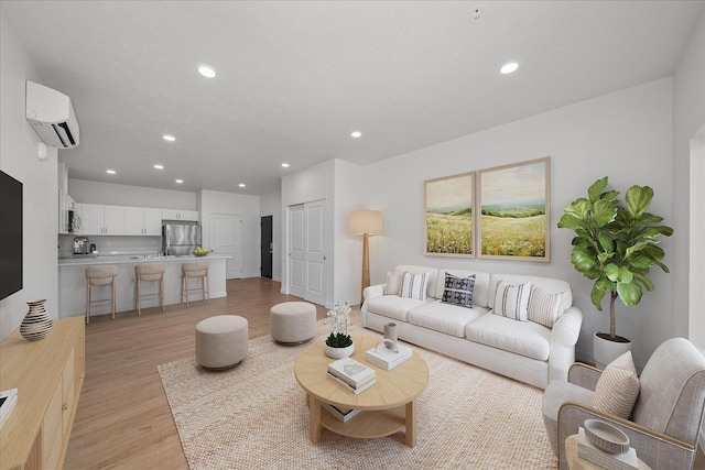 living area featuring recessed lighting, light wood finished floors, and a wall unit AC