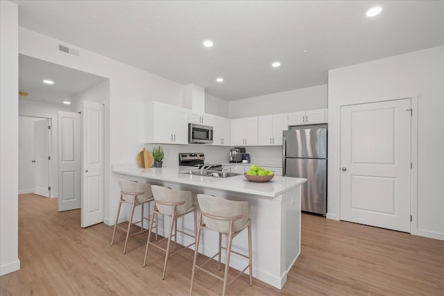 kitchen with light countertops, appliances with stainless steel finishes, visible vents, and a kitchen bar