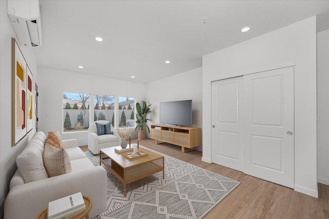 living area with an AC wall unit, baseboards, recessed lighting, and light wood-style floors