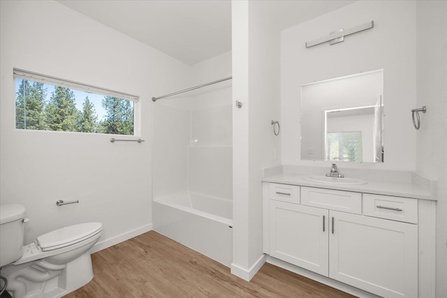 bathroom featuring bathtub / shower combination, vanity, toilet, baseboards, and wood finished floors