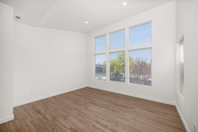 spare room with baseboards, recessed lighting, and wood finished floors