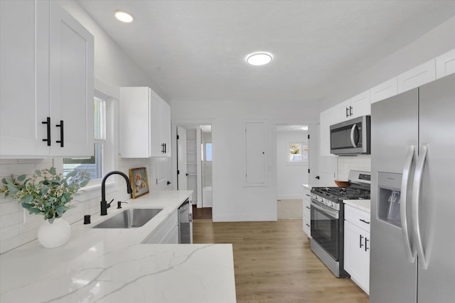 3903 E Hartson Ave, Spokane, WA 99202 - kitchen with appliances with stainless steel finishes, tasteful backsplash, light stone countertops, white cabinetry, and light wood finished floors