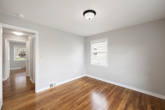 unfurnished room featuring baseboards, visible vents, and wood finished floors