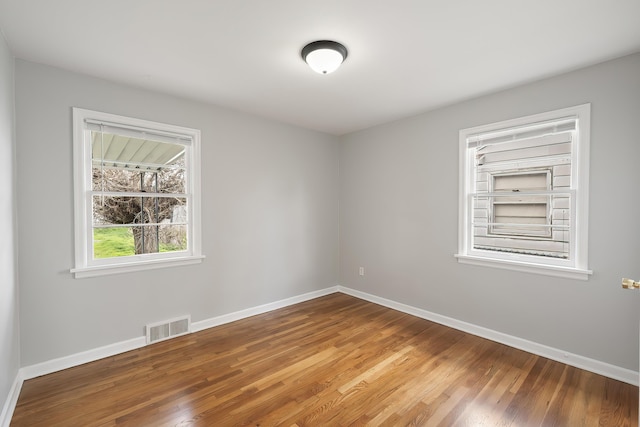 spare room with visible vents, baseboards, and wood finished floors