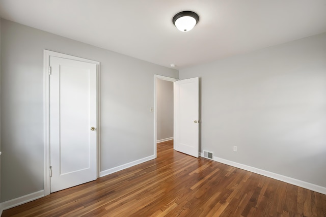 unfurnished bedroom featuring baseboards, visible vents, and wood finished floors