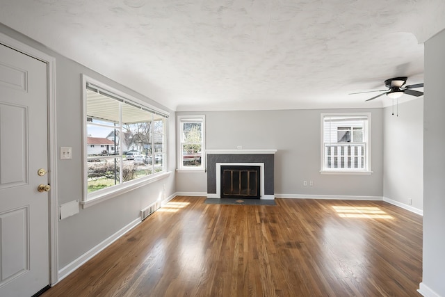 unfurnished living room with baseboards, visible vents, a fireplace with flush hearth, and wood finished floors