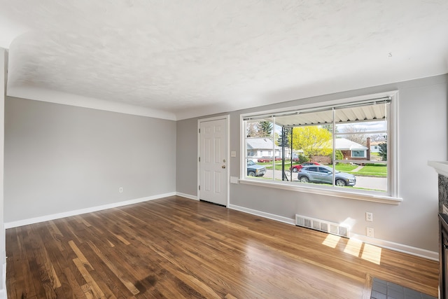 interior space with visible vents, baseboards, wood finished floors, and a fireplace