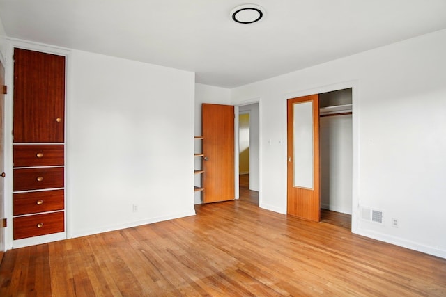 unfurnished bedroom with visible vents, baseboards, wood finished floors, and a closet
