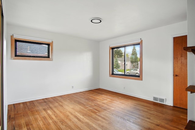 spare room with baseboards, visible vents, and light wood finished floors