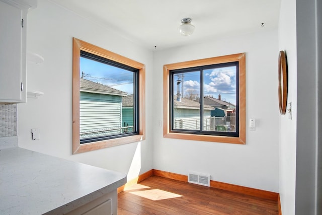 unfurnished dining area with baseboards, visible vents, and wood finished floors