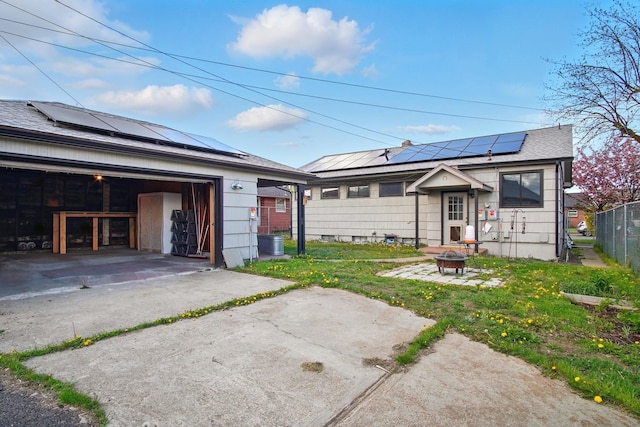 exterior space with a garage, roof mounted solar panels, fence, and a fire pit